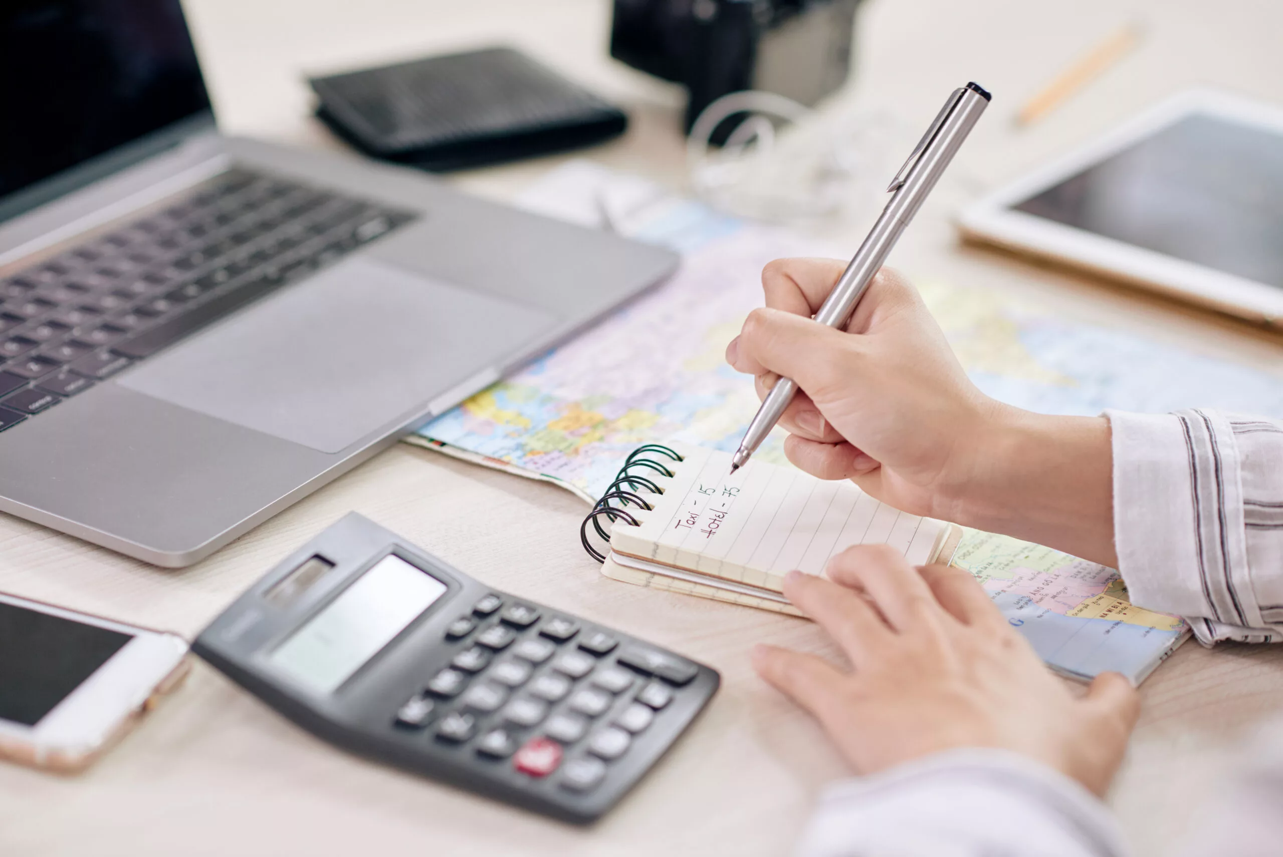 Pessoa fazendo cálculos na calculadora e anotando no bloco de notas